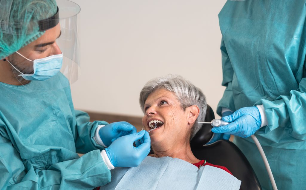 Two prosthodontists work with a mature woman to help replace missing teeth and restore her smile.