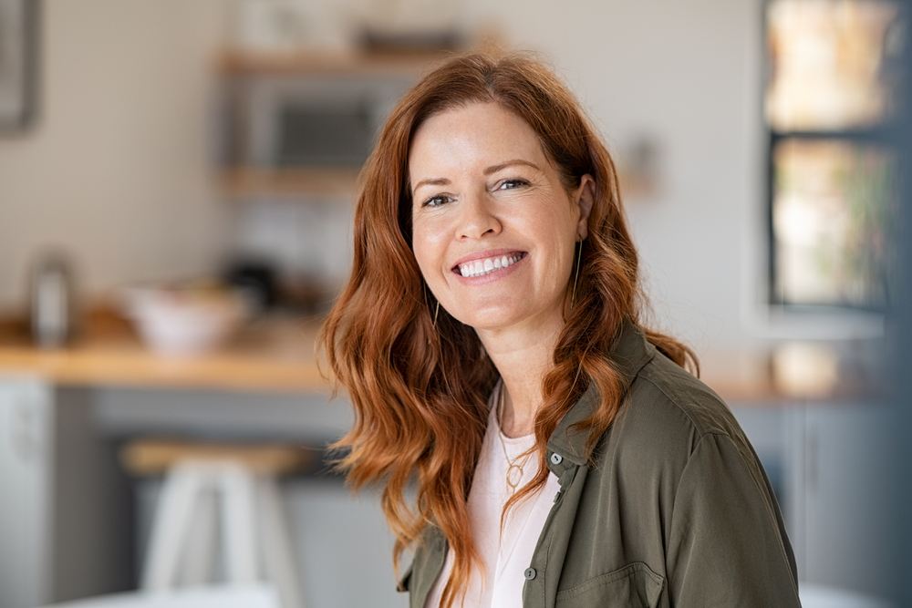  A mature woman with long red hair smiles after learning the prosthodontics definition. 