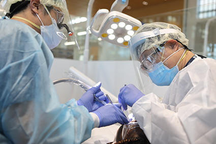  Dentists at Penn Dental Family Practice in protective gear examine a patient. 