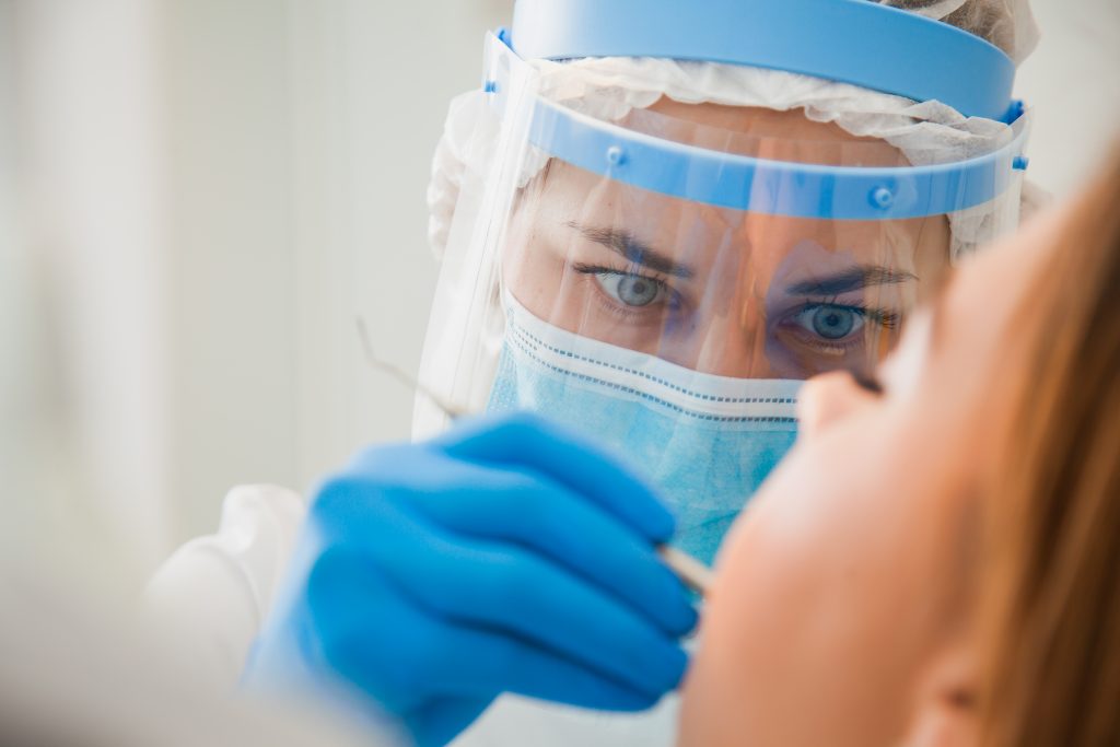  Young female dentist curing patient's teeth filling cavity.