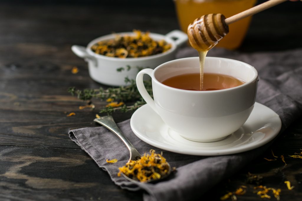 Cup with herbal tea and honey and dry herbal tea