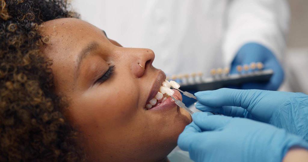A cosmetic dentist fits a female patient with dental veneers. 