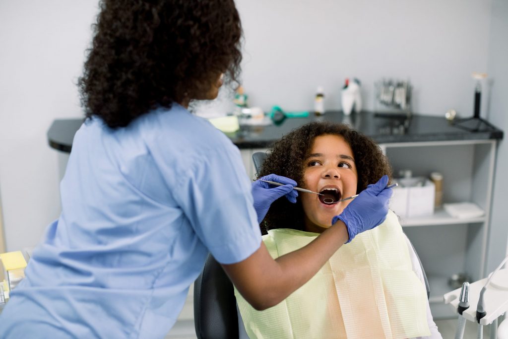 Tween girl looks at the dental hygienist during a dental appointment. 