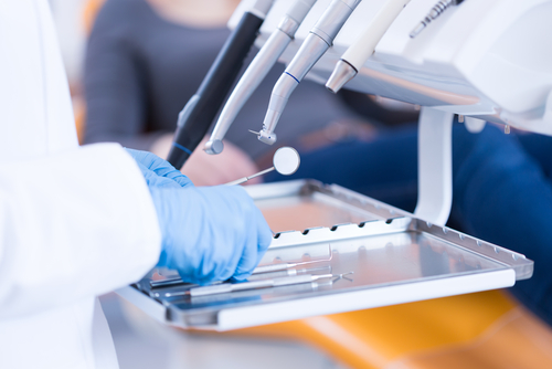 Closeup of dentist hands in gloves examining equipment.