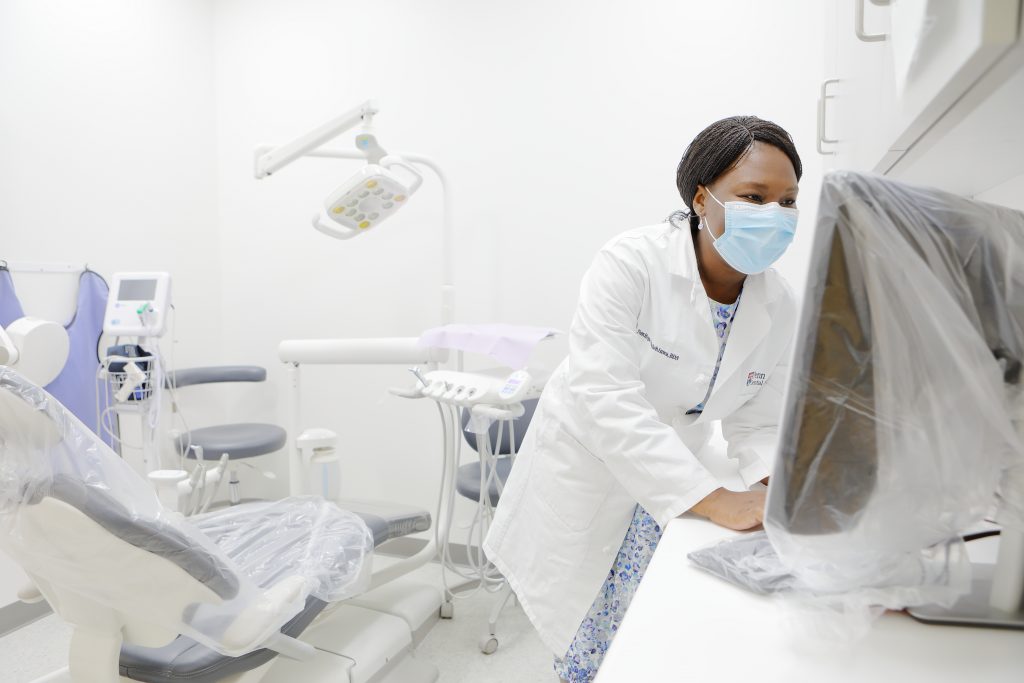 A female dentist takes a break from seeing patients, but is still wearing facemask in a fully protected dental area.