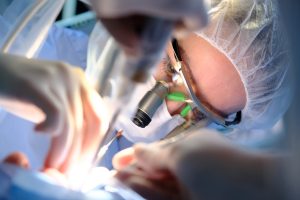 A female prosthodontist performs oral surgery on a patient. 