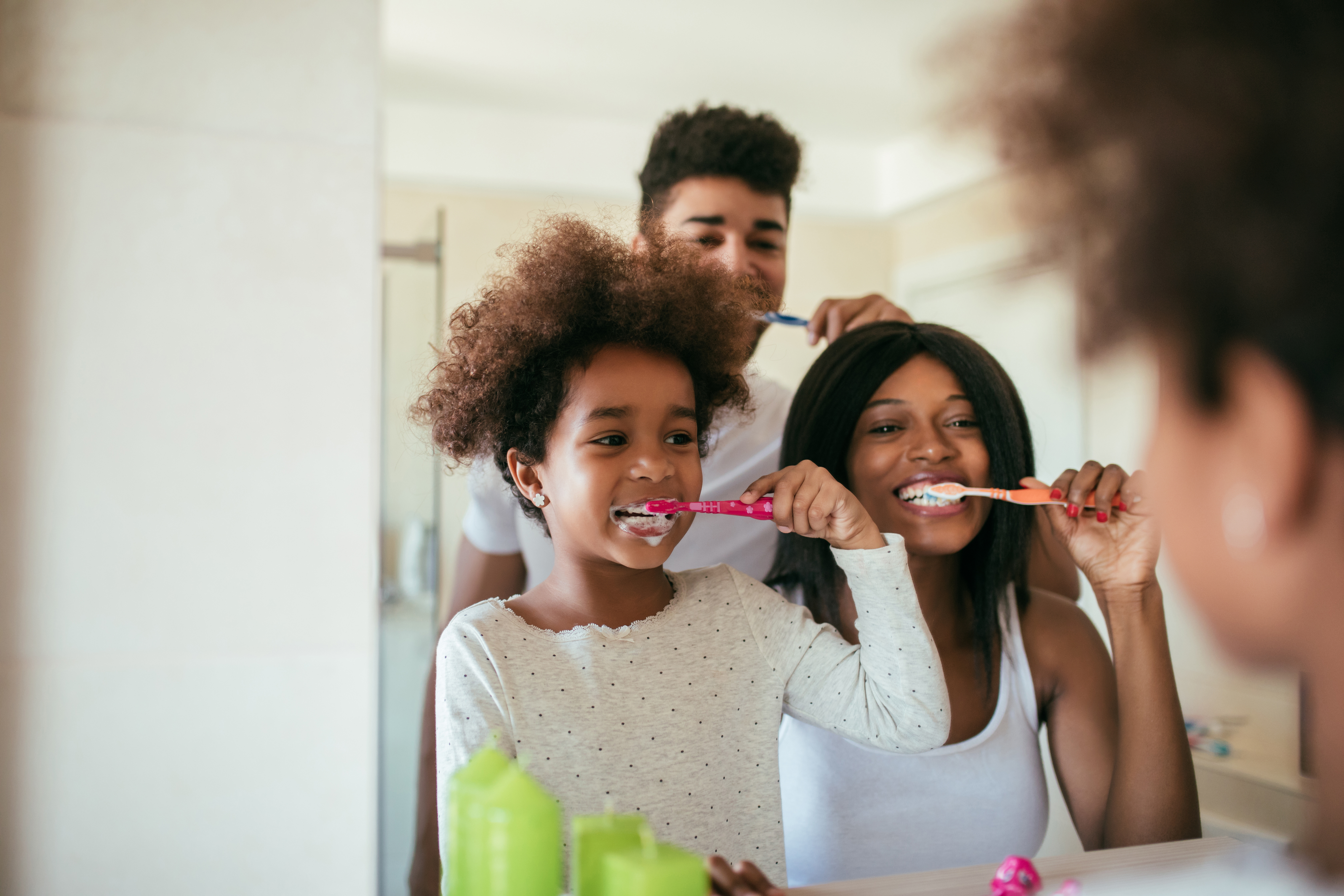 Smiling Black family brushes their teeth together. 