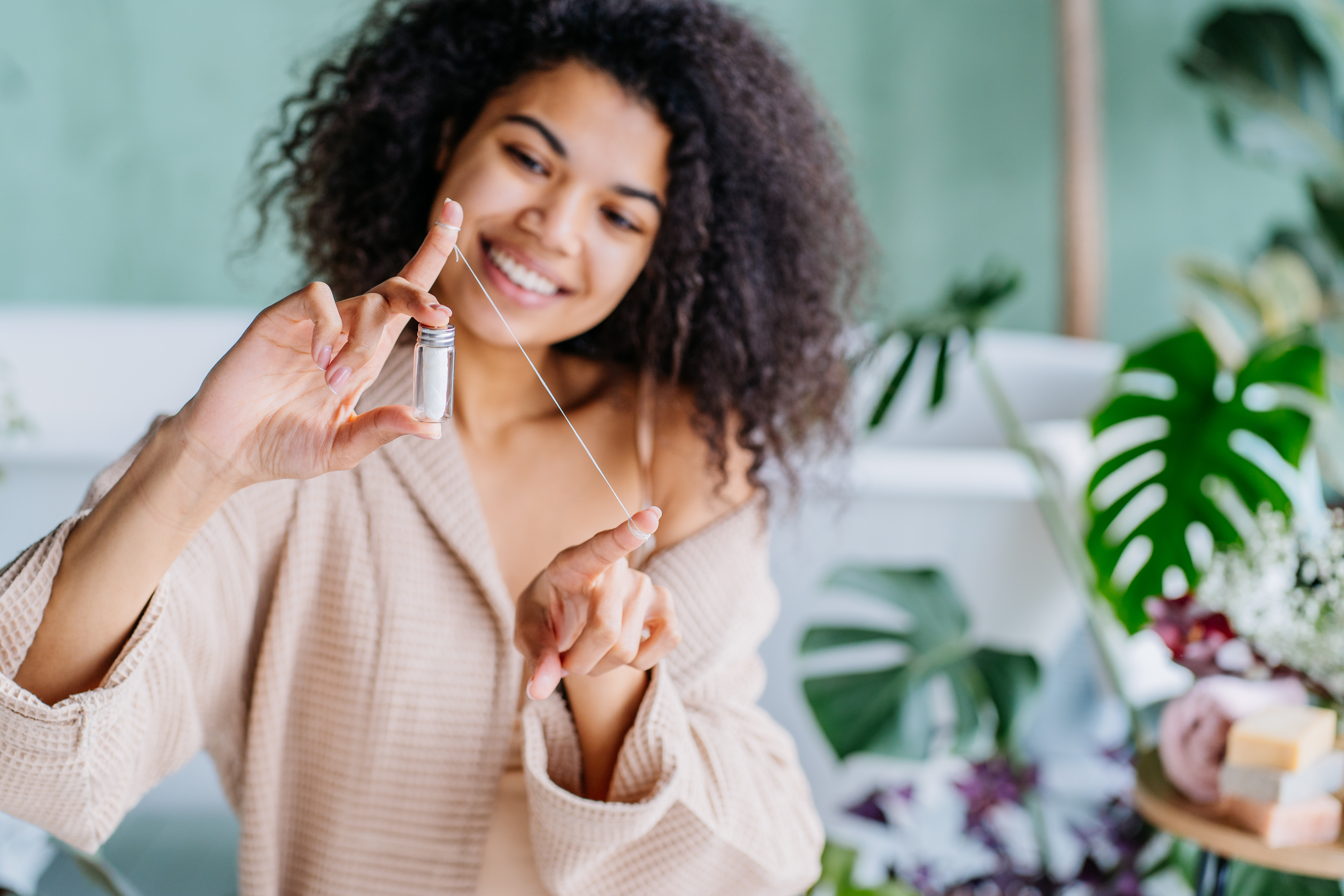 Smiling Black woman uses dental floss. 