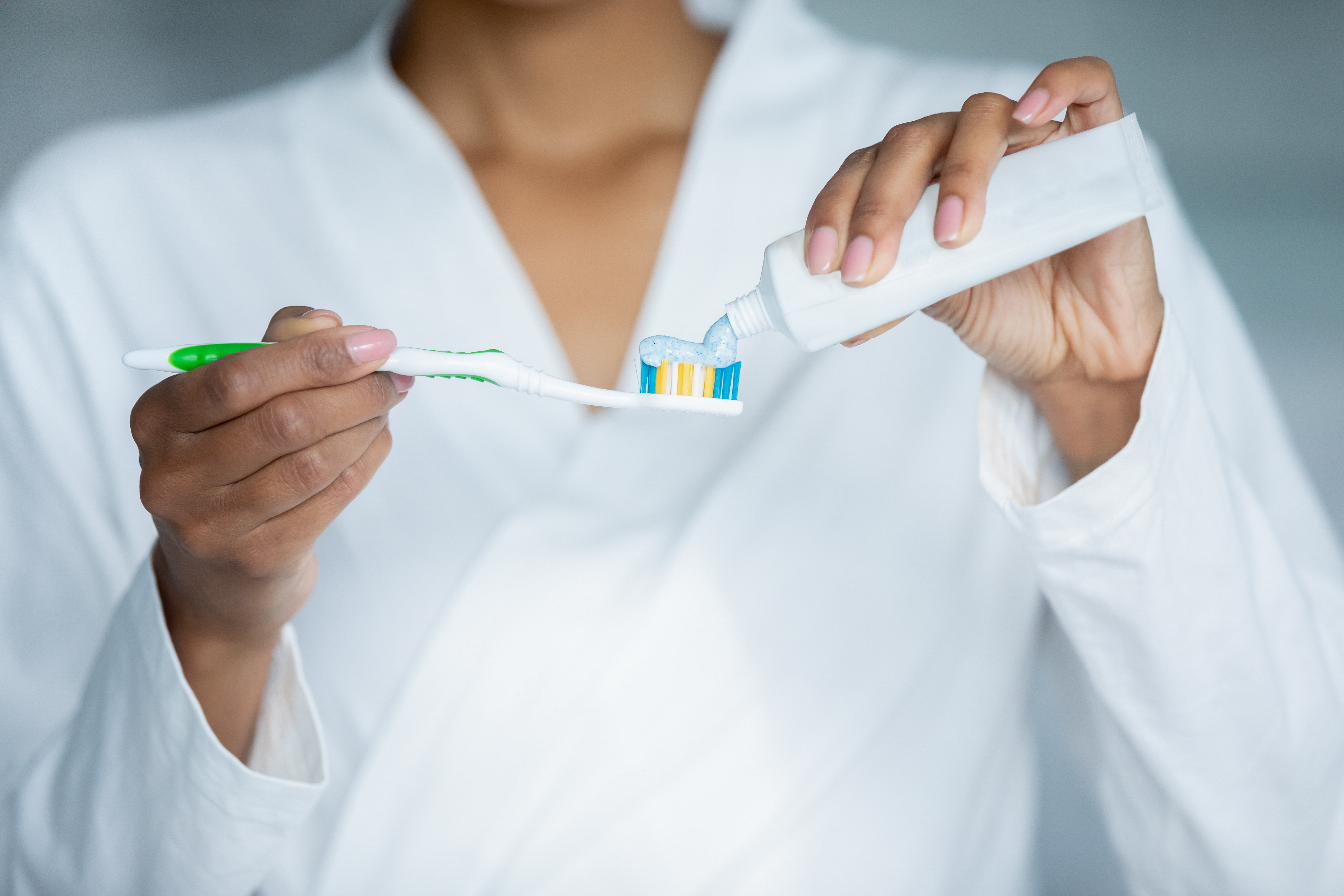 Woman puts toothpaste on a toothbrush.