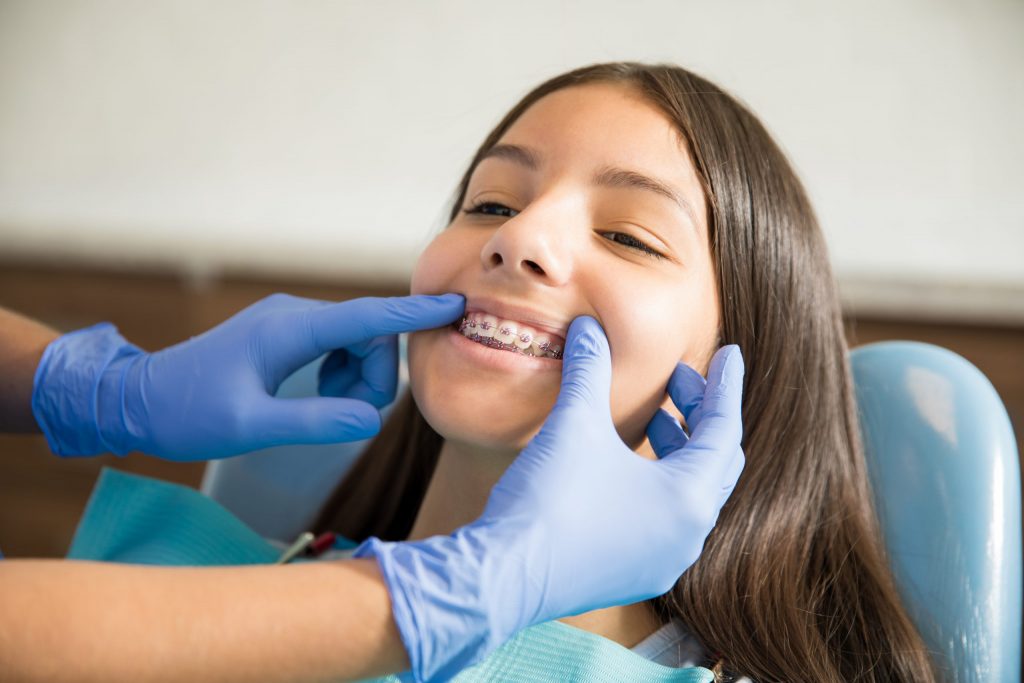 Teenage girl with braces has her teeth examined by an orthodontist. 
