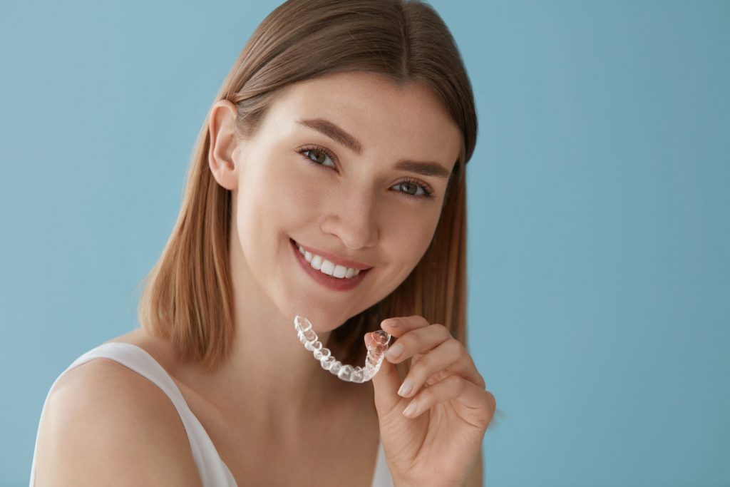 Woman with white smile, healthy straight teeth using clear removable braces