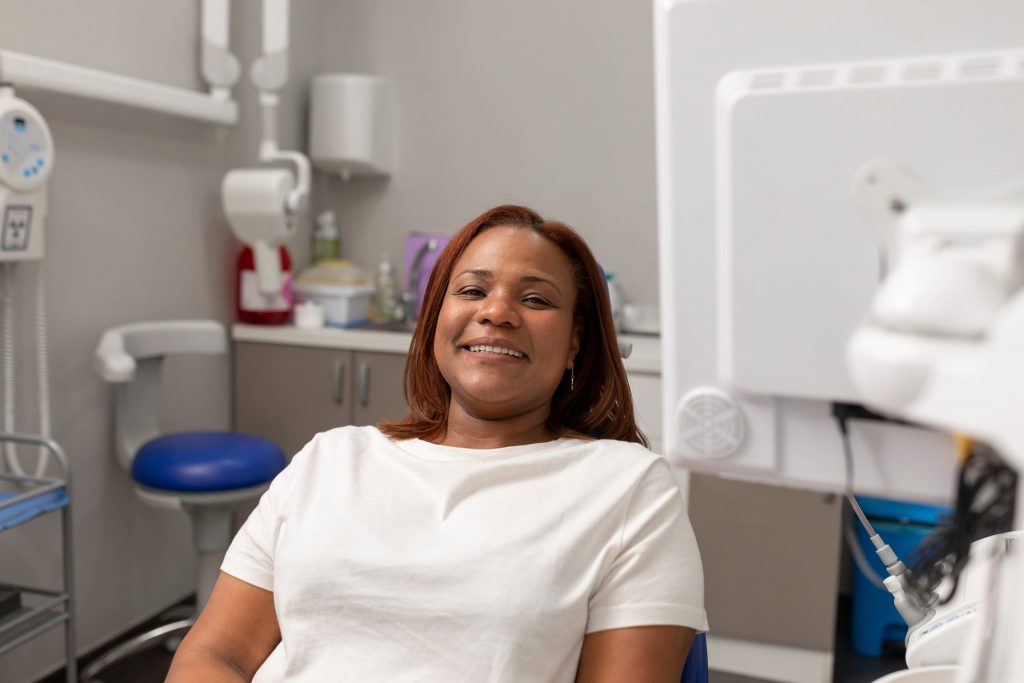 Smiling woman sits in dental chair after periodontal treatment