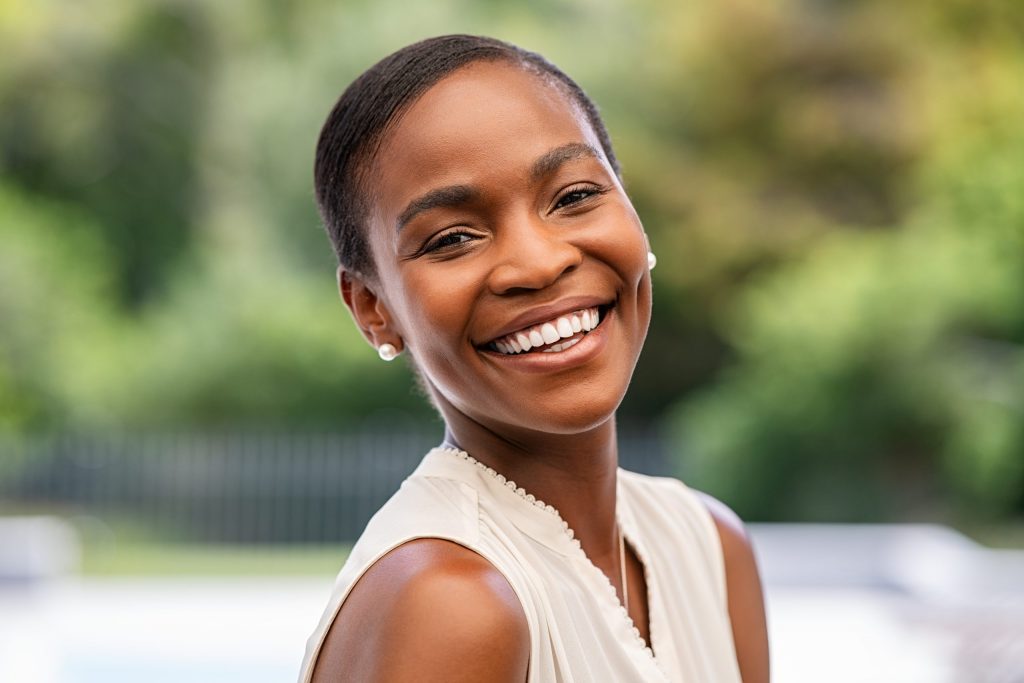 A woman with short hair smiles brightly because her periodontal gum disease has been cured at PDFP. 