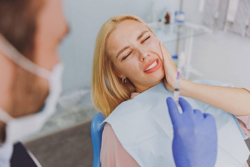  A young woman in the chair at the dentist suffers from pain from periodontal gum disease and is there for treatment. 