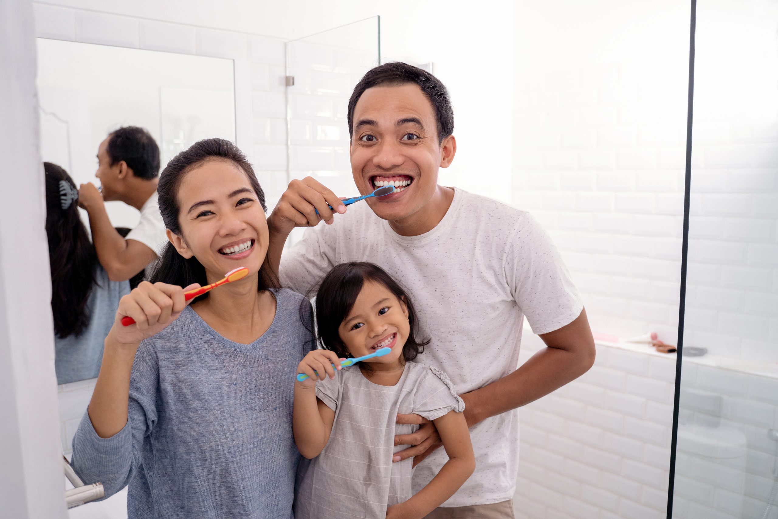 A family of three brushing their teeth together. 