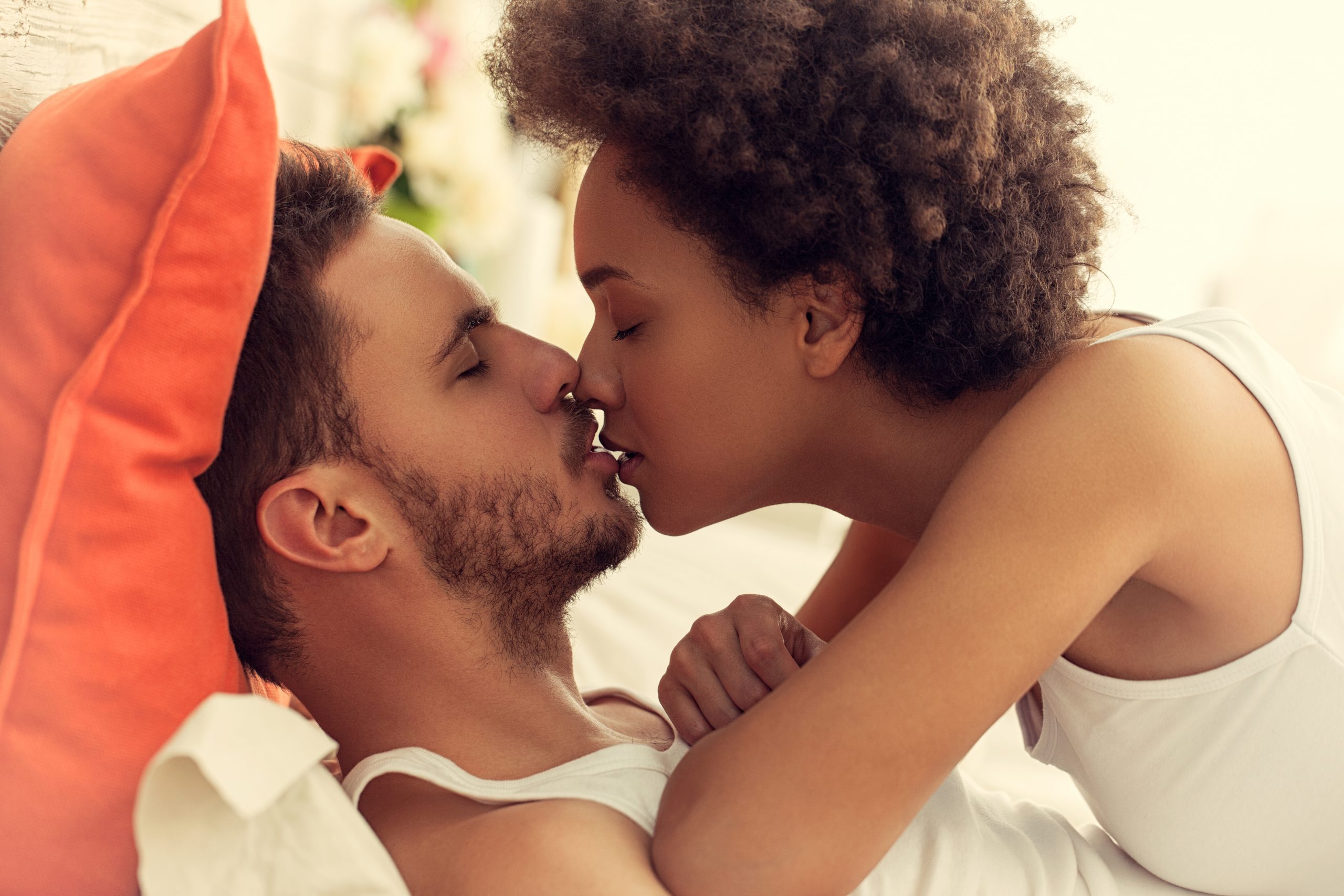 A woman and man kiss in bed. Human papillomavirus (HPV) infection is a sexually transmitted oral cancer risk factor.
