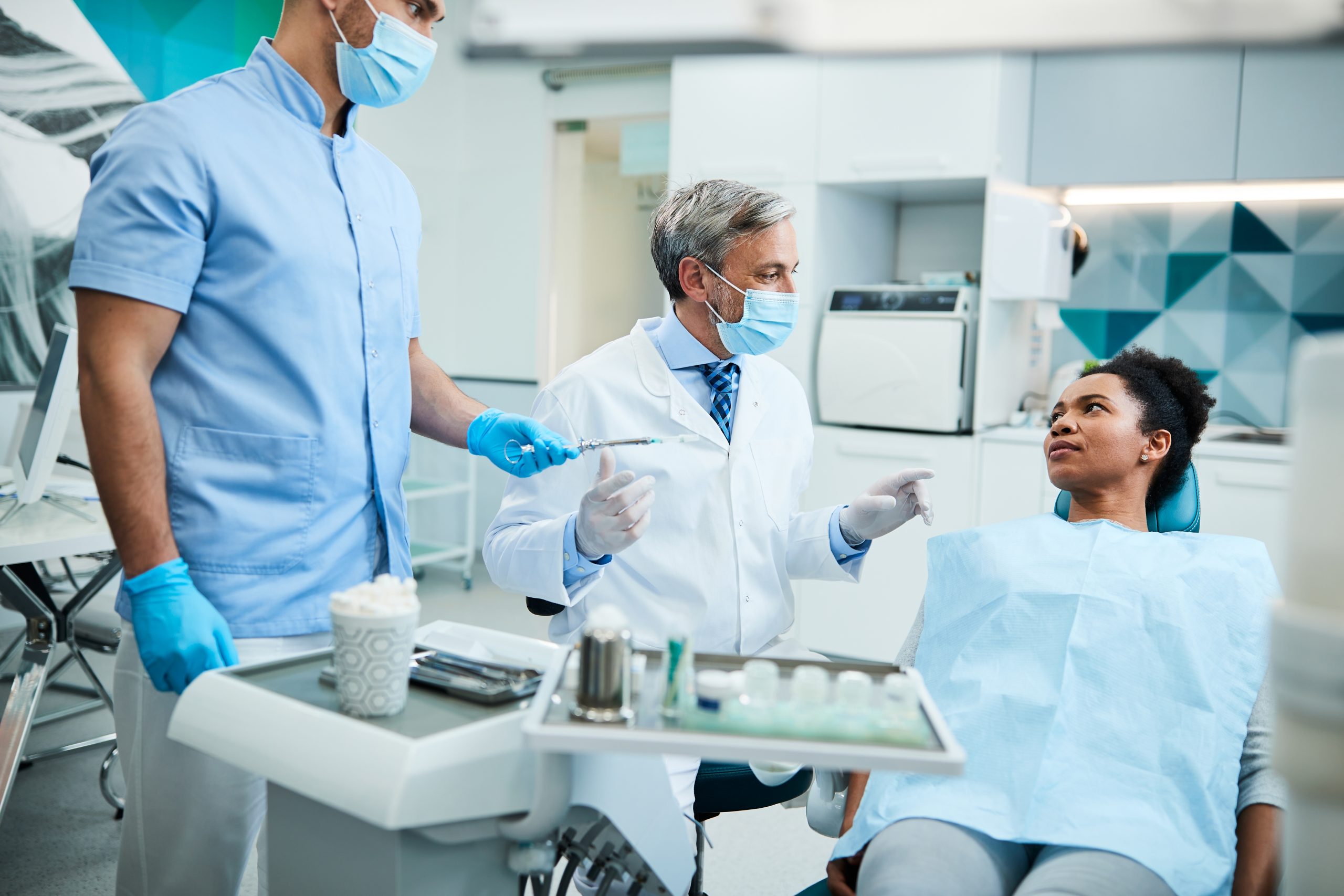 A Philadelphia oral medicine specialist talks with a medically complex patient in a dental chair, as a dental assistant stands near.