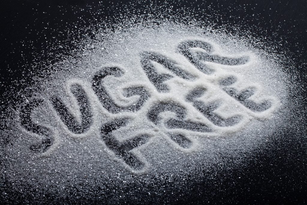 The words “sugar free” are written in sugar on the top of a black surface.