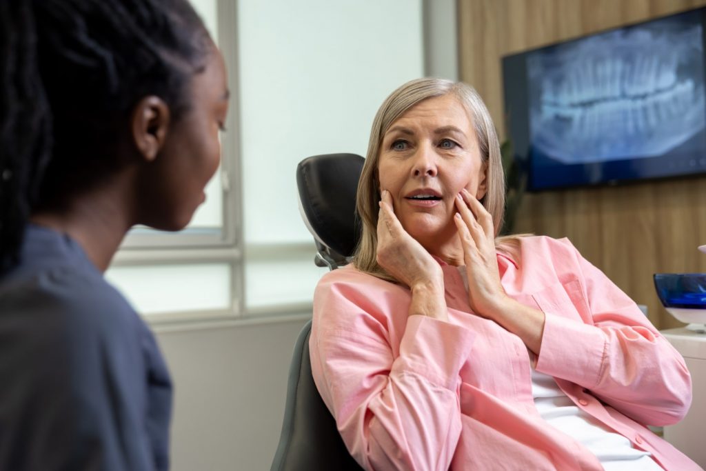 A middle-aged woman talks to her dentist about her oral health and menopause concerns. 