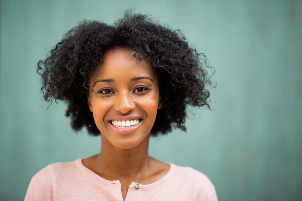 A young woman smiles now that her tooth pain and migraine connection have been discovered and cured.