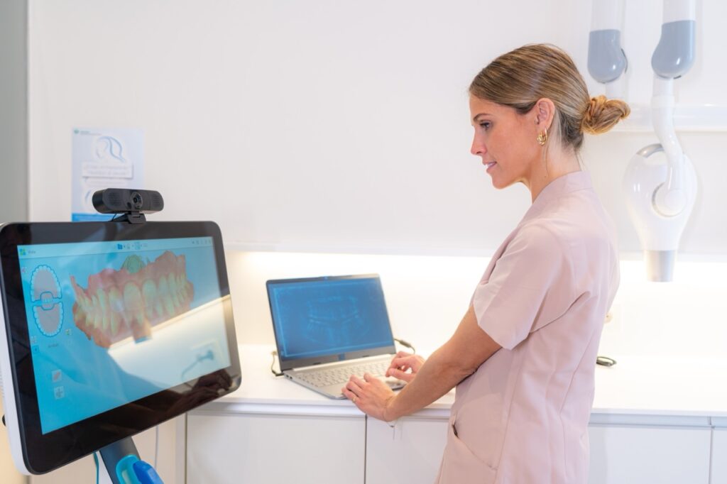 Dentist uses dental artificial intelligence on laptop computer to analyze digital scan of patient’s mouth for potential oral health problems. 