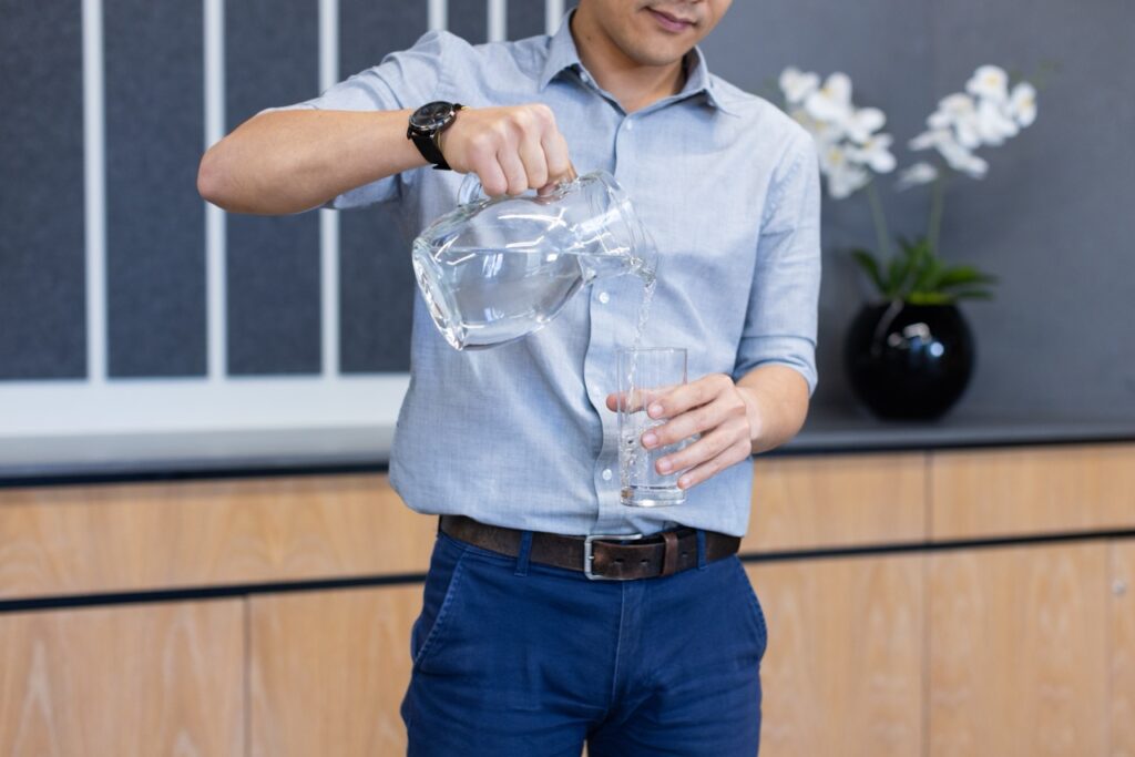 Man pours pitcher of fluoridated water into his glass.